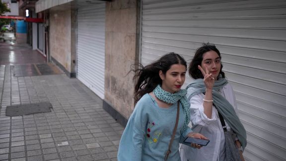 Two Iranian women walk along a street-side in the strong winds without wearing the mandatory Islamic headscarf in downtown Tehran,on June 8, 2023.