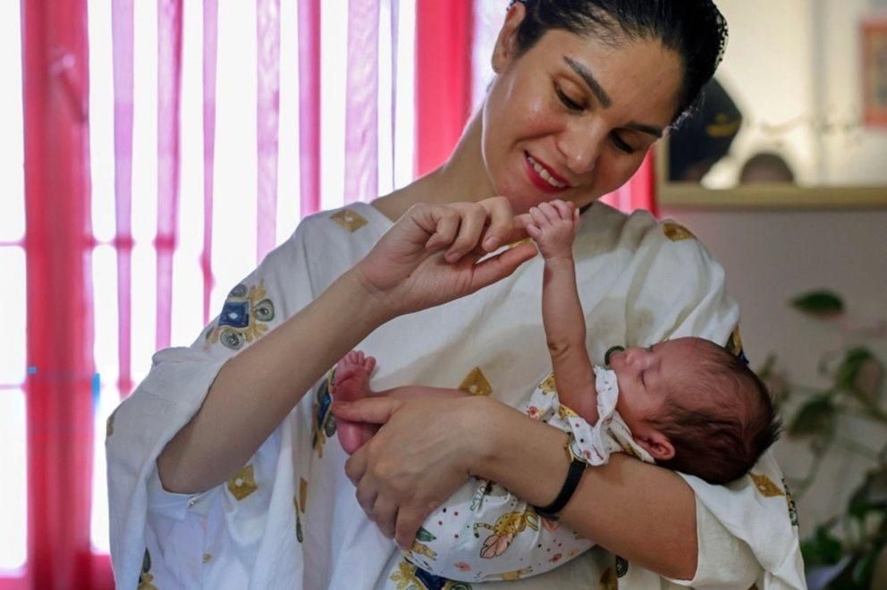Iranian influencer holds a baby placed through Iran’s Mizban temporary foster care program in this photo.