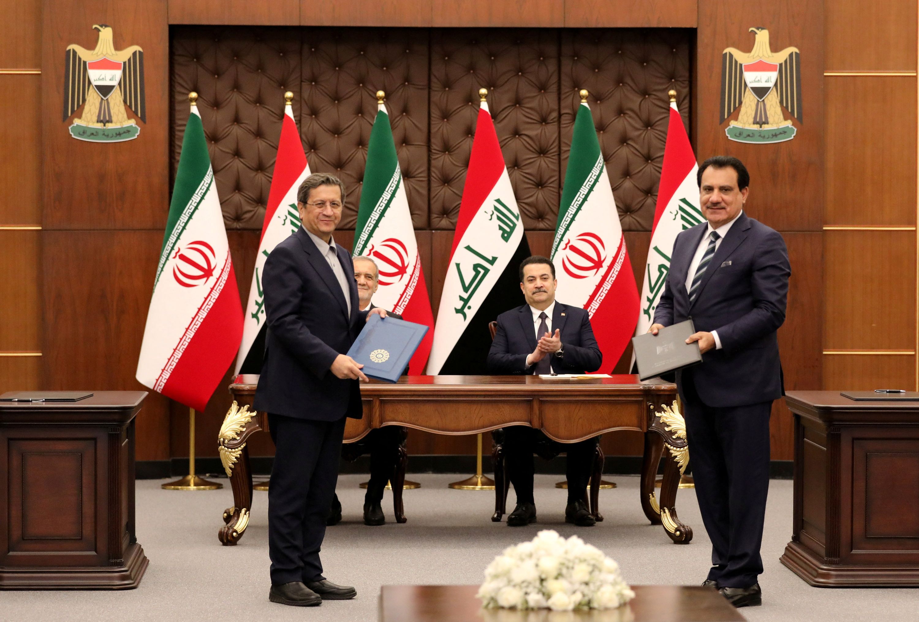 Iranian President Masoud Pezeshkian and Iraqi Prime Minister Mohammed Shia al-Sudani react as Chairman of the Baghdad Chamber of Commerce, Firas Rasool exchanges a Memorandum of Understanding with the Iranian Minister of Trade during the signing ceremony of Memoranda of Understanding between Iraq and Iran at the government palace in Baghdad, Iraq, 11 September 2024. 