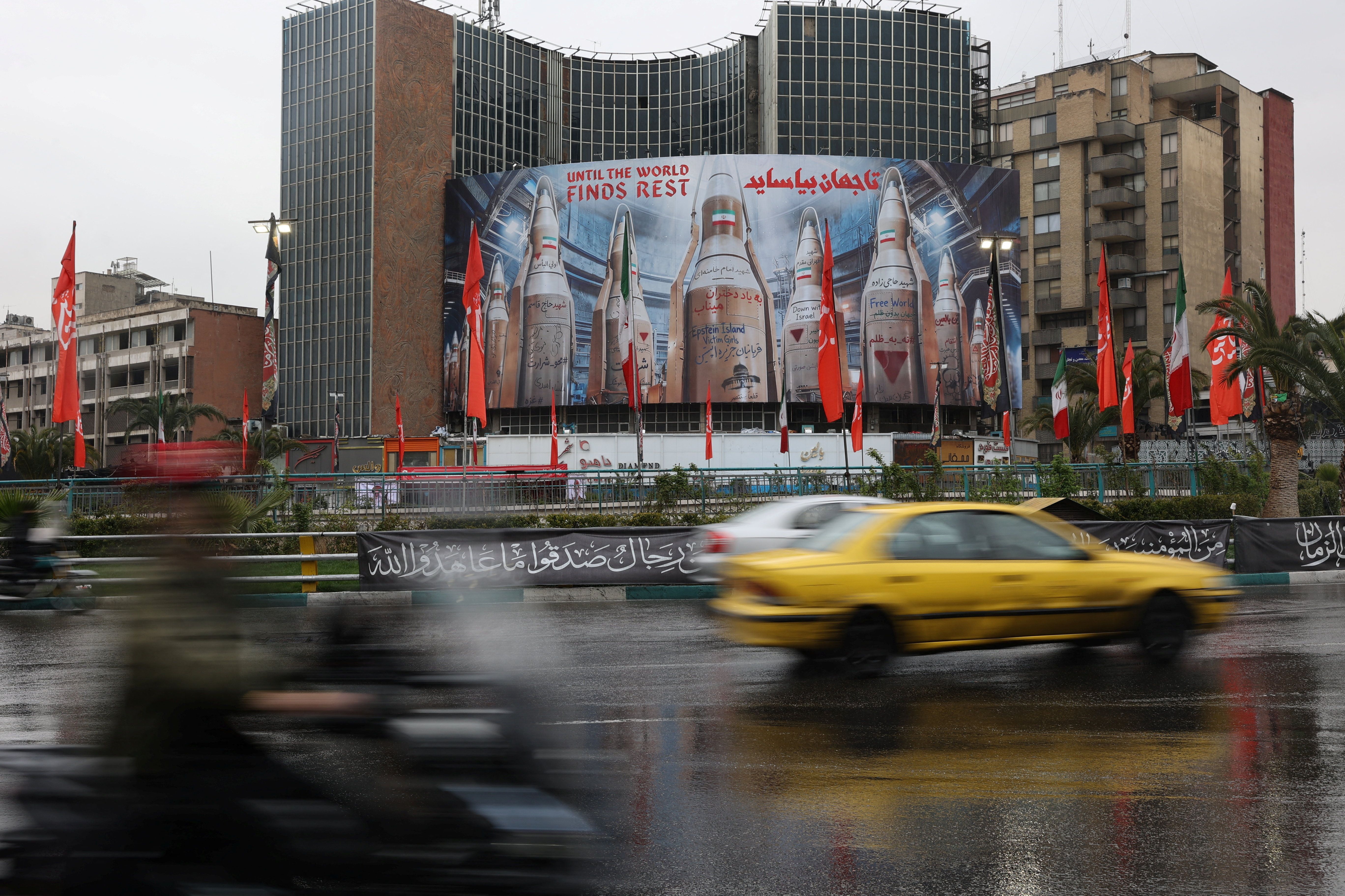 Vehicles ply near a billboard with an image of Iranian missiles on a building, amid the US-Israeli conflict with Iran, in Tehran, Iran, March 16, 2026.