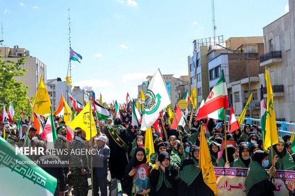 Iranians carrying flags of Iran’s proxy militias during a regime-sponsored demonstration for Quds day in Tehran on April 14, 2023