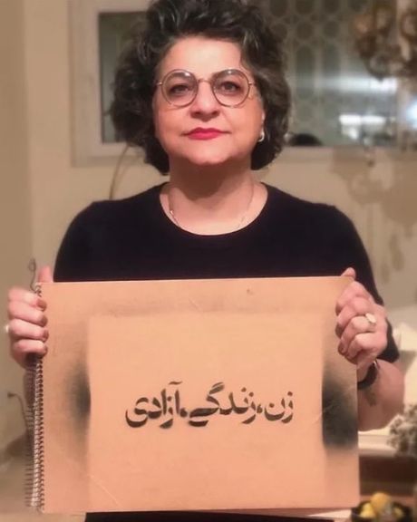 Mina Akbari holding a sign that reads, "Woman, Life, Freedom"—a slogan that emerged from the protests in Iran following the death of Mahsa Amini in September 2022