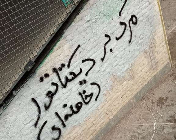 A slogan written on a wall says, "Death to the dictator, Khamenei"
