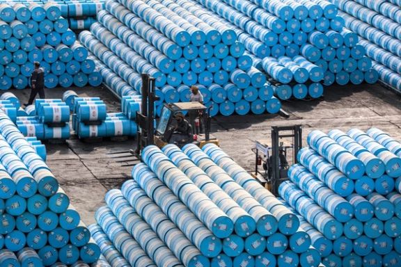 Workers move stacked barrels of oil products at a storage site in Iran, September 2025