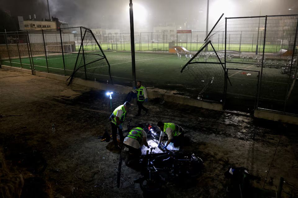 Emergency personnel inspect the area after rockets were launched across Lebanon's border with Israel which, according to Israel's ambulance services, people were killed, at a soccer pitch in Majdal Shams, a Druze village in the Israeli-occupied Golan Heights, July 27, 2024.