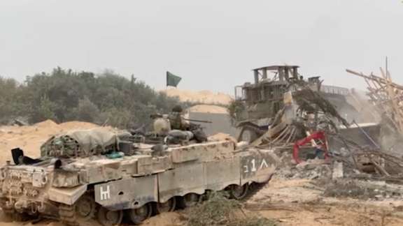 An Israel Defense Forces (IDF) armored vehicle waits as an armored bulldozer clears a debris-strewn path in a location given as Gaza. Octo. 29, 2023