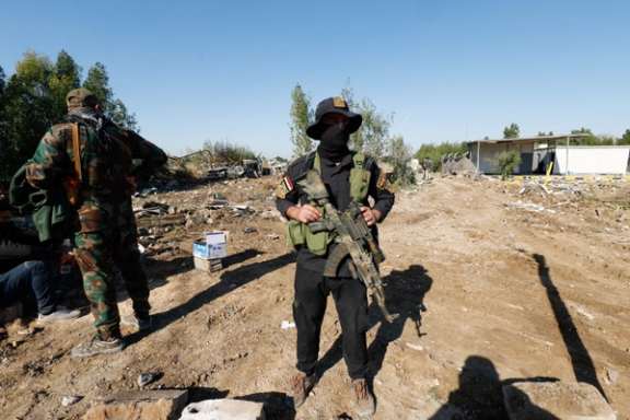 Fighter of the Iraqi Kataib Hezbollah militia group stands the site of a US airstrike, in Hilla, Iraq December 26, 2023.