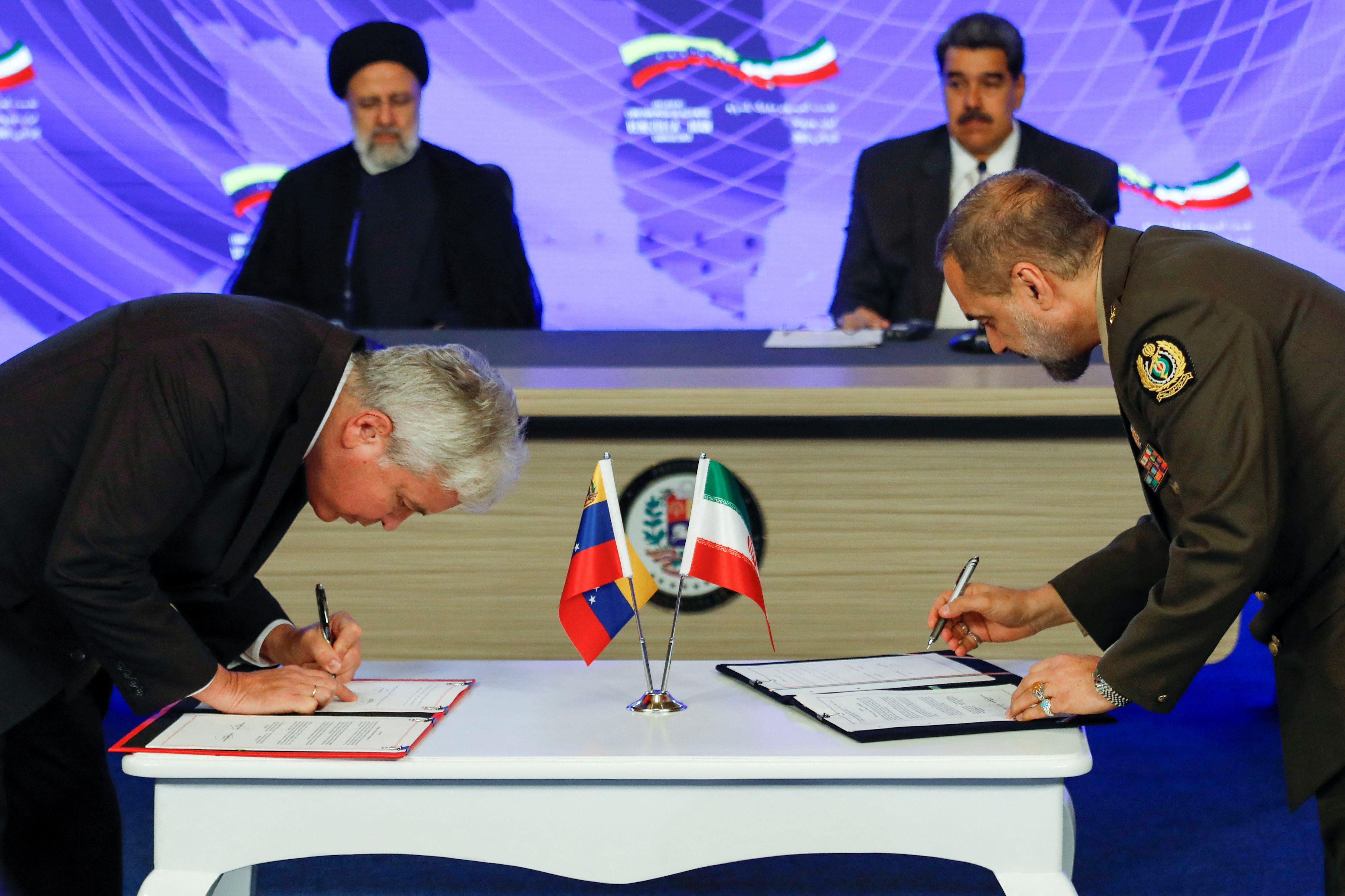 Venezuela's President Nicolas Maduro and Iranian President Ebrahim Raisi look on as Iranian Defense Minister Mohammad Reza Ashtiani and Venezuela's Minister of Agriculture Wilmar Castro sign agreements during a meeting at the Miraflores Palace, in Caracas, Venezuela June 12, 2023. 