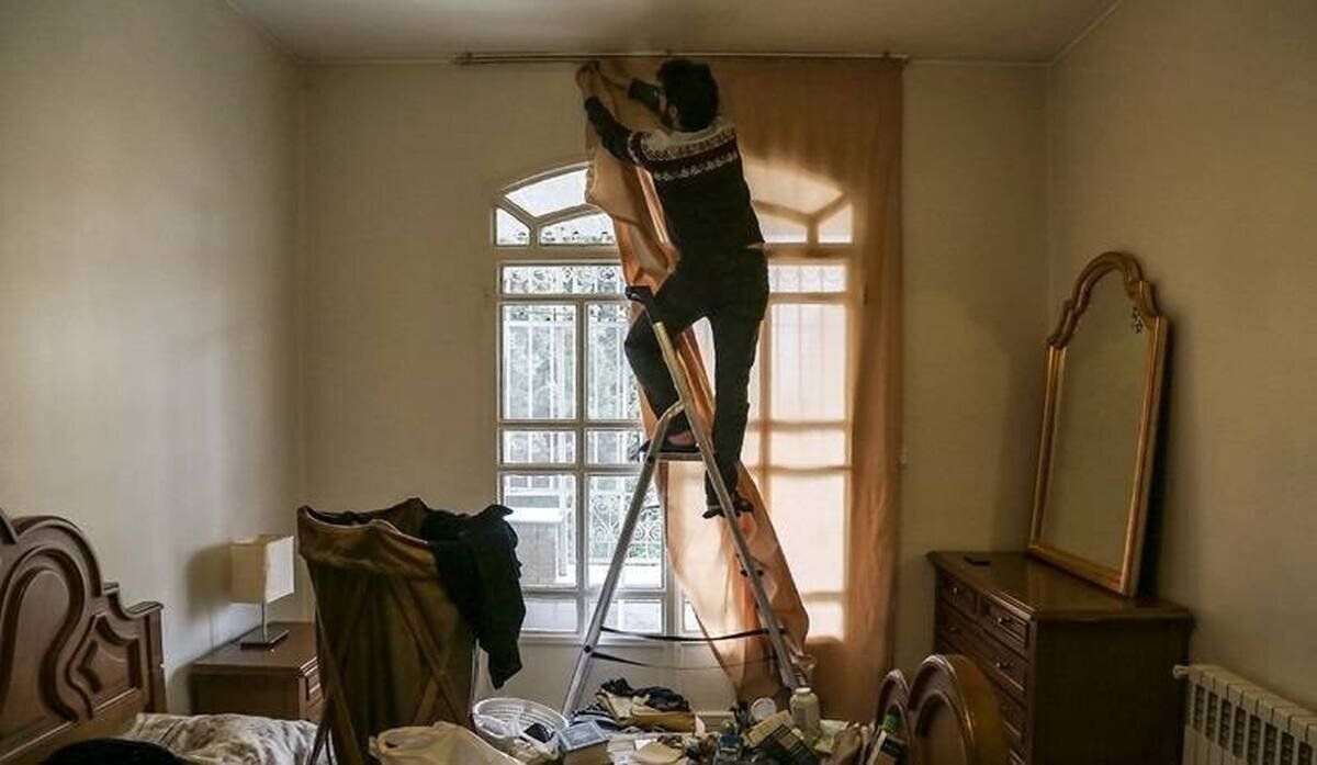 An Iranian man installs curtains at home as part of preparations ahead of the Nowruz new year celebrations.