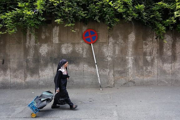 A woman walks pulling along her shoppings, Hamedan, Iran, June 8, 2025