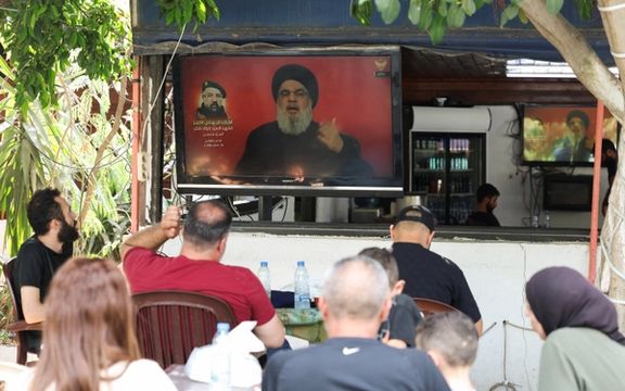 گروهی در حال تماشای سخنرانی تلویزیونی حسن نصرالله، دبیرکل حزبالله، شهر صور لبنان، ۱۱ مرداد