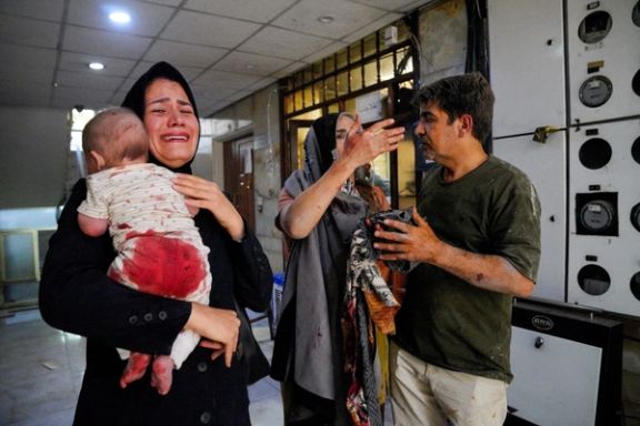 A woman carries her child following the Israeli strikes on Iran, in Tehran, June 15 2025.