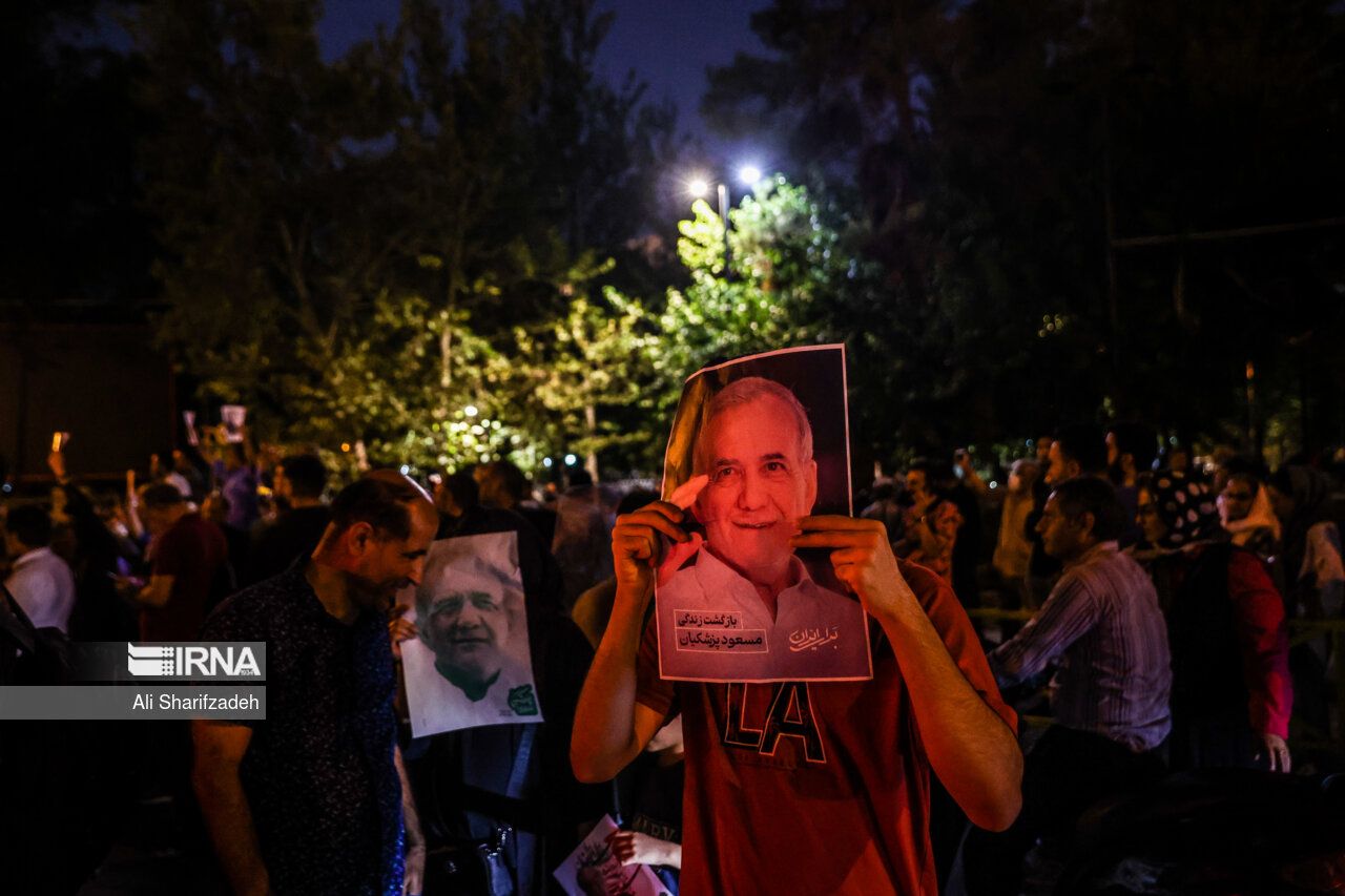 A man holding a campaign poster of presidential candidate Masoud Pezeshkian, Tehran (June 2024) 