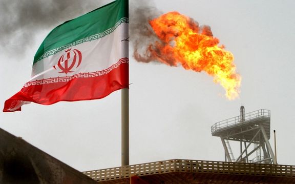 A gas flare on an oil production platform is seen alongside an Iranian flag in the Gulf July 25, 2005.