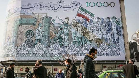 People walking past a mural at Tehran’s Enqelab square showing the Iranian 10,000-rial banknote worth less than two cents now