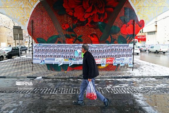 An Iranian man walks past campaign posters for the parliamentary election in Tehran, Iran, February 2024.