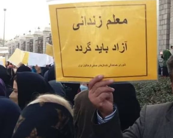 A protest sign reads "Jailed teacher must be freed"