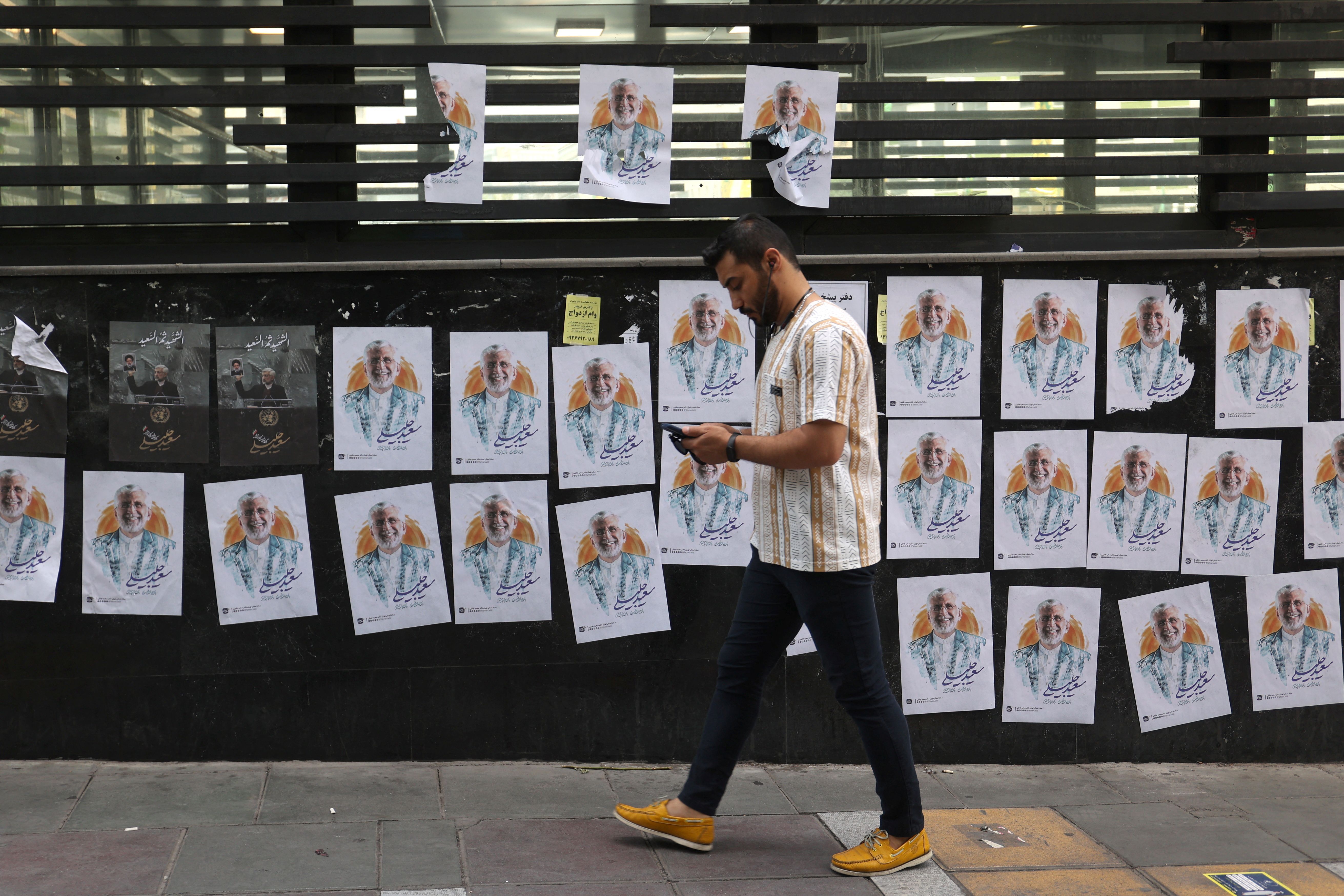 A man walks past posters of Iranian presidential candidate Saeed Jalili on a street in Tehran, Iran, July 4, 2024.