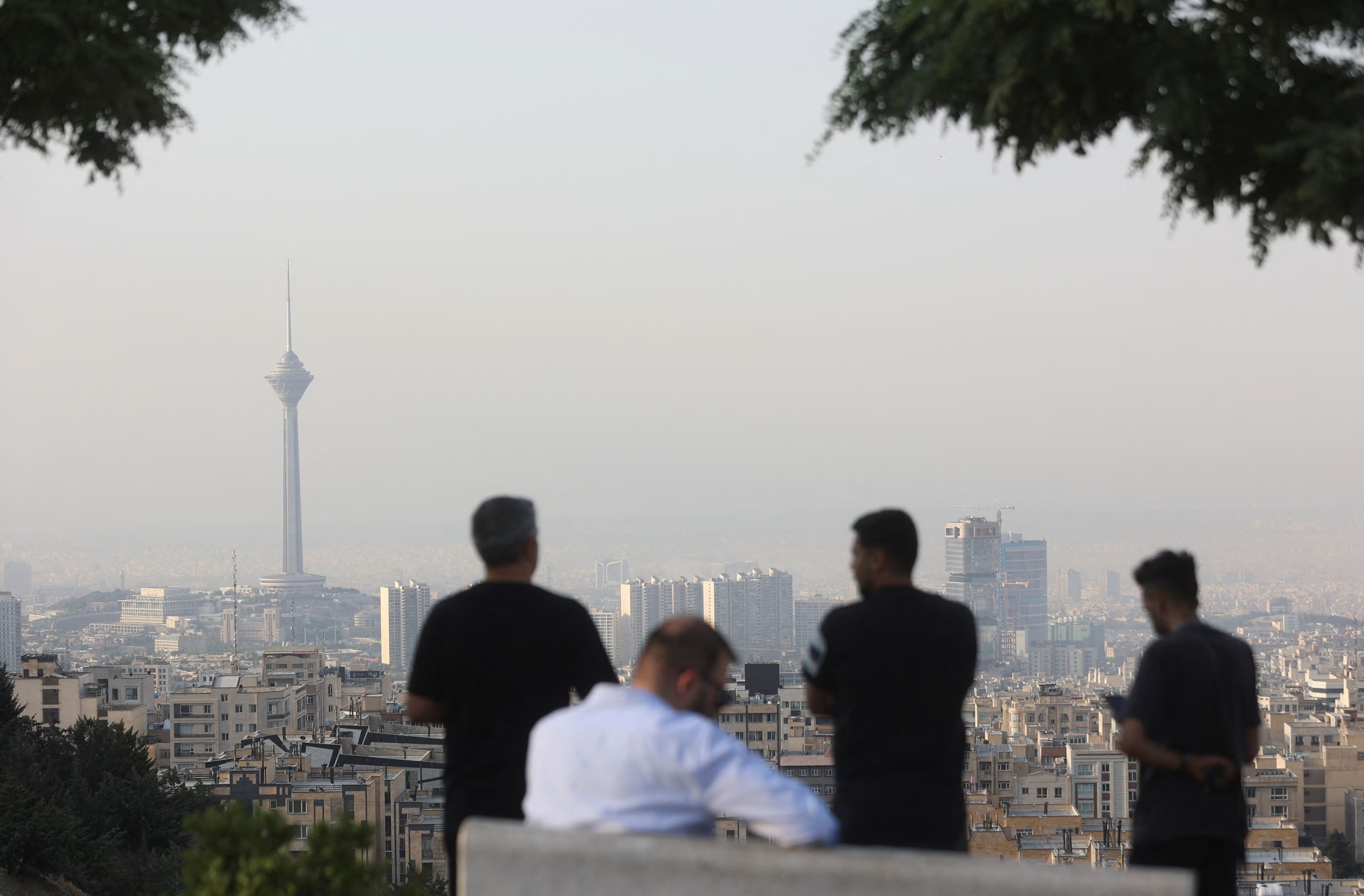 Men view the cityscape in the aftermath of Israeli strikes, in Tehran, Iran, June 13, 2025. 
