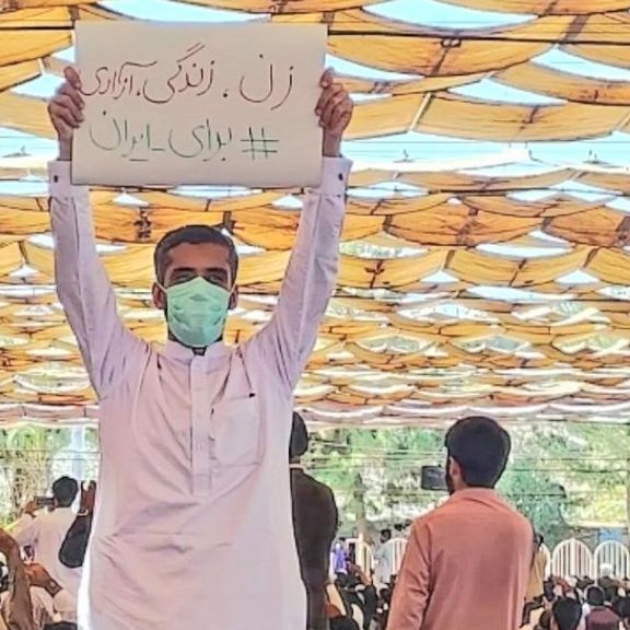A protester in Zahedan holding a banner of the main slogan of the current wave of protests: Women, Life, Liberty