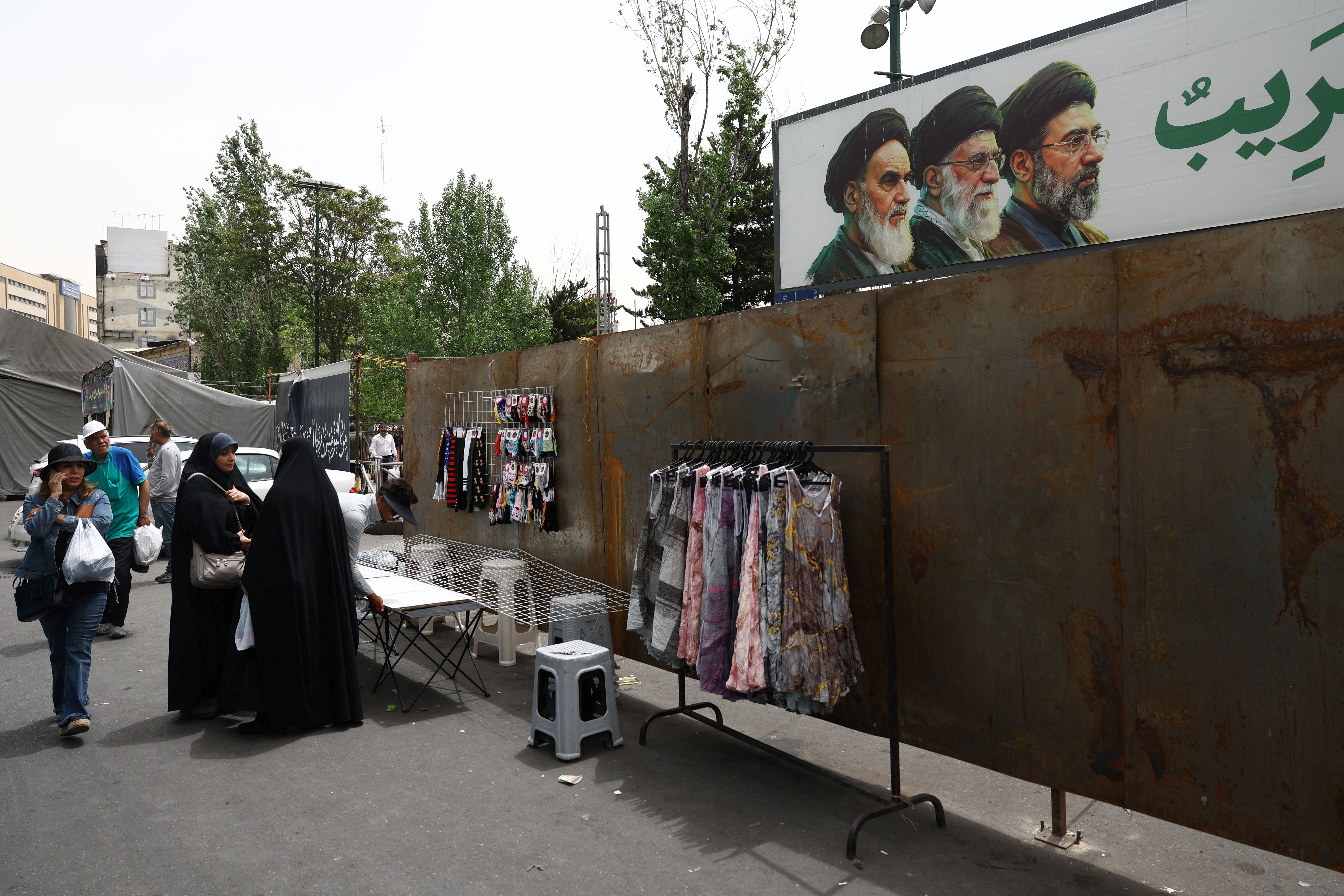 People walk past a banner depicting the late leader of the Islamic Revolution Ayatollah Ruhollah Khomeini, late Supreme Leader of Iran Ayatollah Ali Khamenei and Iran's new Supreme Leader Mojtaba Khamenei, in Tajrish Square in Tehran, Iran, May 4, 2026.