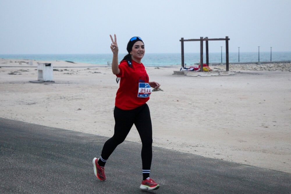 A young woman gestures towards camera while running the marathon in Iran's Persian Gulf island of Kish, December 5, 2025