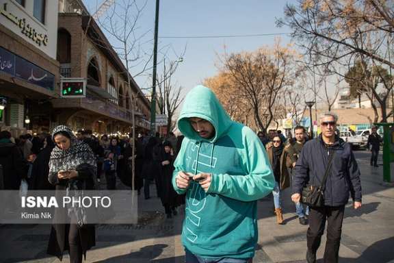 People looking at their cellphones on a street near Tehran's bazaar