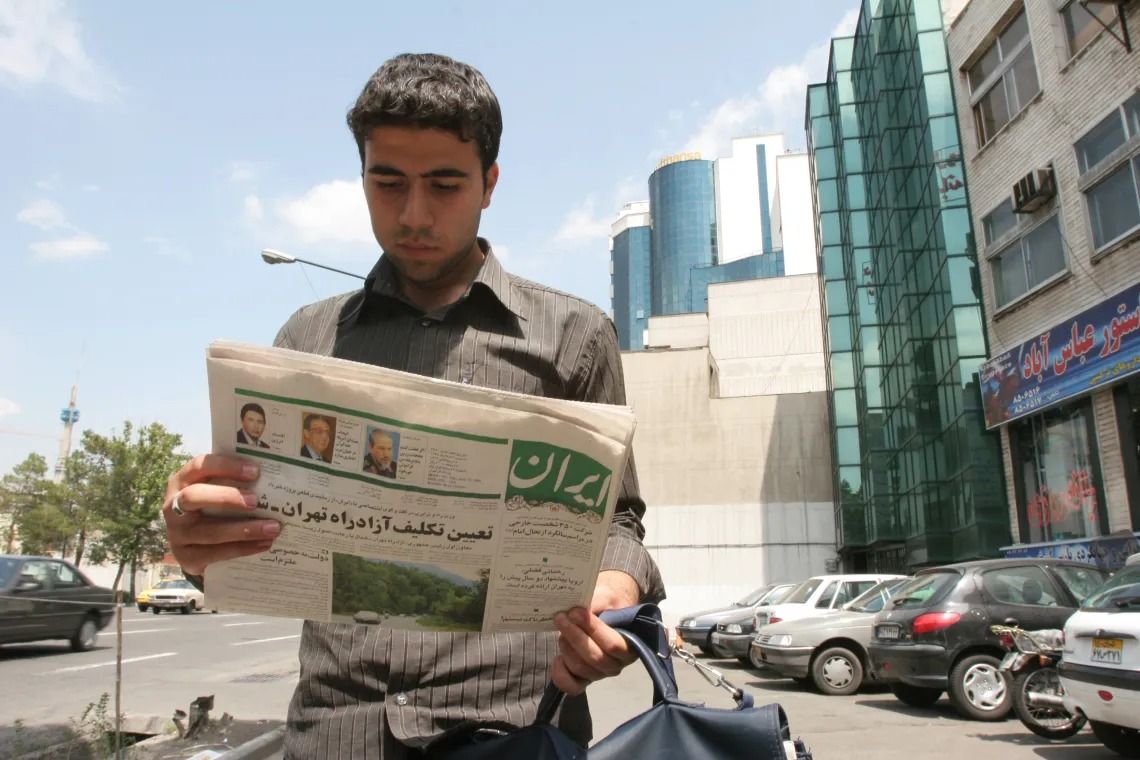 File photo of a man reading a copy of Iran newspaper on a Tehran street