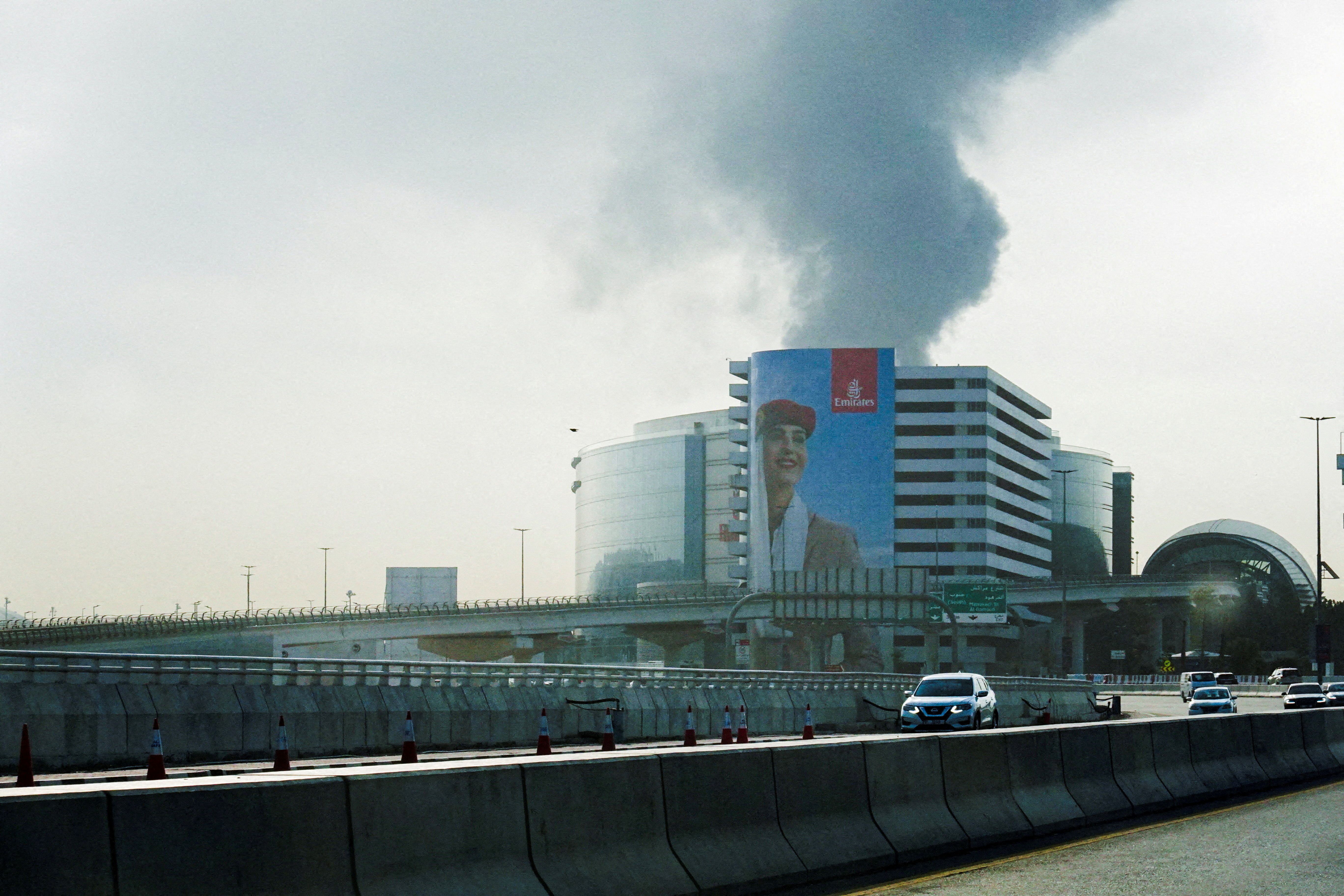 Smoke rising from an area near the Dubai International Airport is seen through the windshield of a vehicle, after a drone attack hit a fuel tank in Dubai, United Arab Emirates, March 16, 2026, 