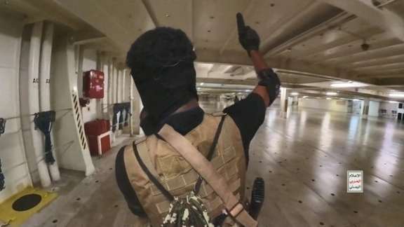 A Houthi fighter holds up a pistol in the cargo area of the Galaxy Leader cargo ship in the Red Sea in this photo released November 20, 2023.