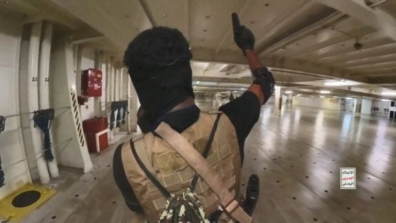 A Houthi fighter holds up a pistol in the cargo area of the Galaxy Leader cargo ship in the Red Sea in this photo released November 20, 2023.