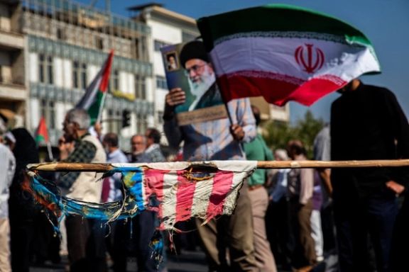 Iranian pro-government demonstrators display a torn flag of the United States, a picture of Supreme Leader Ali Khamenei and the Islamic Republic's flag