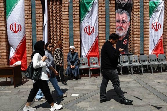 People walk past Iranian flags and a portrait of slain commanders in Tehran, Iran, April 20, 2026