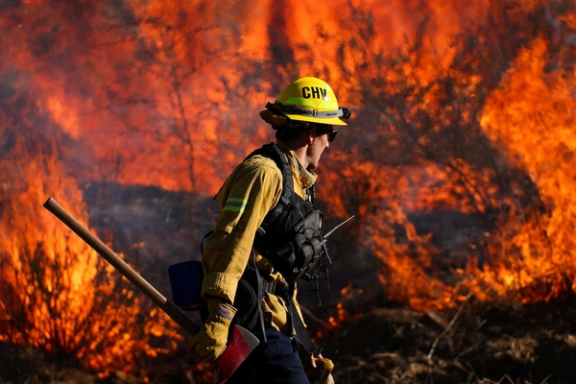 A firefighter works to extinguish the Highland Fire, a wind driven wildfire near Aguanga, California.