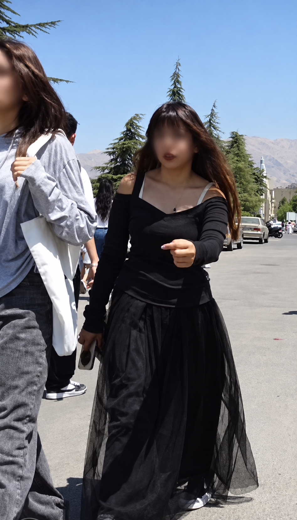 Women without mandatory hijab walk along a street in Iran.