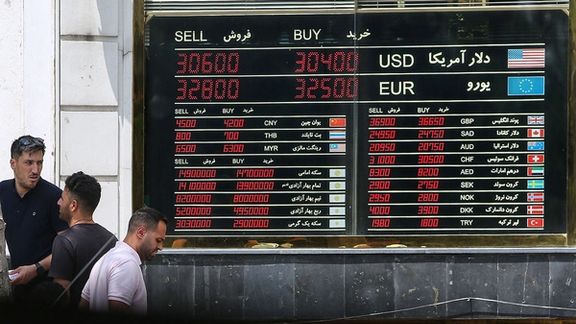 File photo of people in front of a board that shows exchange rates against rial