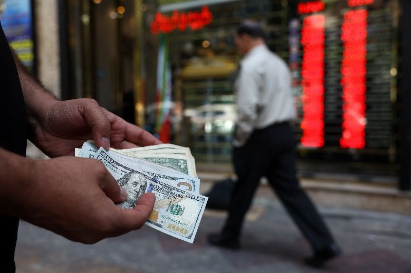 A man counts US dollar banknotes outside a currency exchange in Tehran, Iran.