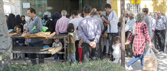 Iranians stand in line outside a bakery