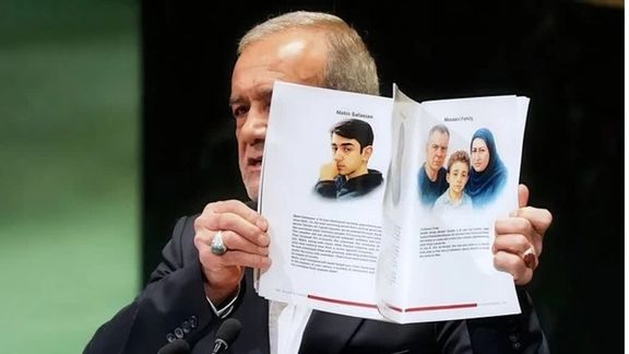 Pezeshkian holds up a booklet containing biographies of Iranians killed by Israel in a June war during his speech before the UN.