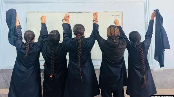 A number of schoolgirls removing their headscarves in support of the protests