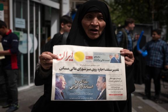 A veiled Iranian woman holds a newspaper featuring portraits of Iranian Foreign Minister Abbas Araghchi and Steve Witkoff, White House special envoy, while she shows her protest against Iran and US negotiations in downtown Tehran, Iran, on April 9, 2025.