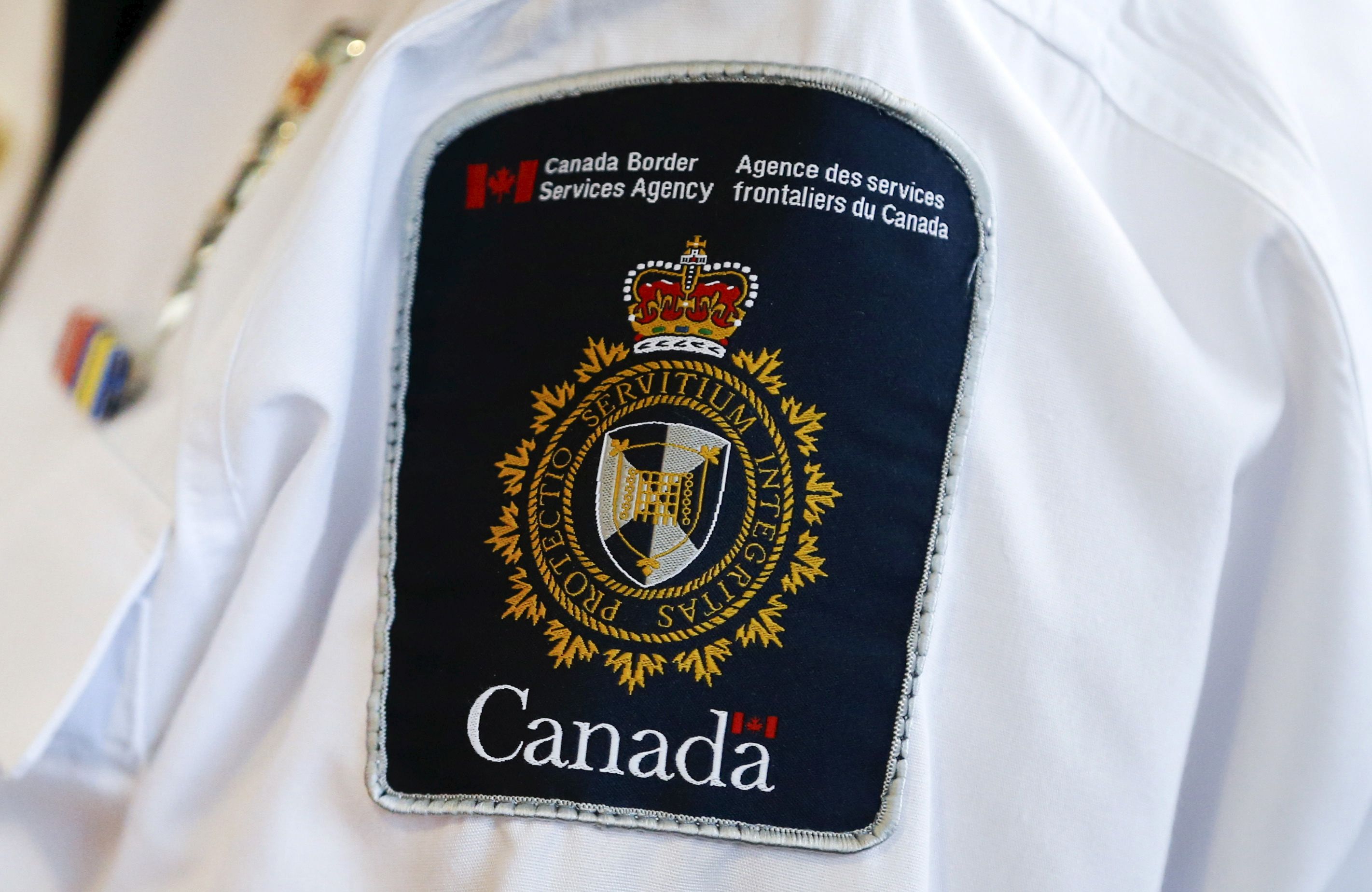A Canada Border Services Agency (CBSA) logo is seen on a worker. 
