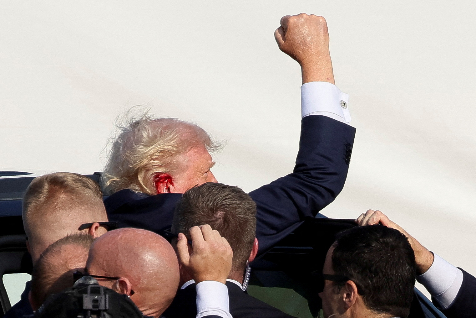 Donald Trump gestures as he gets into a vehicle with the assistance of U.S. Secret Service personnel after he was shot in the right ear during a campaign rally at the Butler Farm Show in Butler, Pennsylvania, US, July 13, 2024.