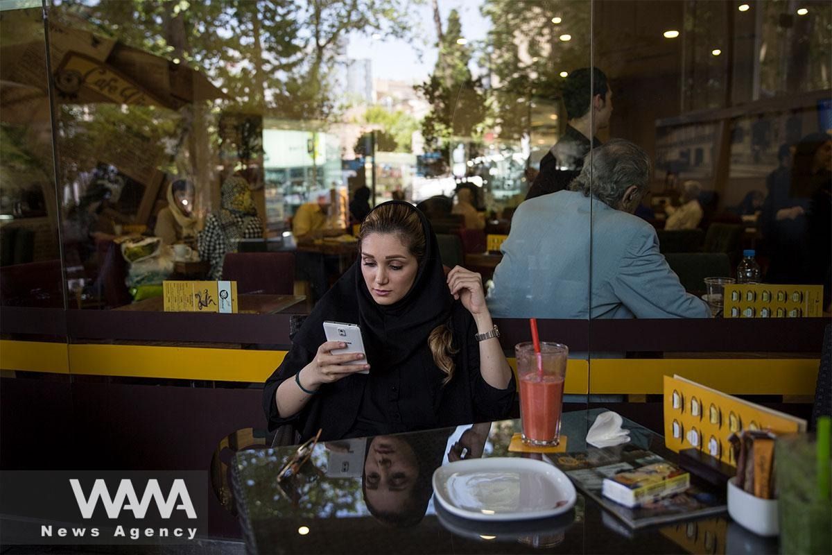A woman checks her phone at a café in Tehran.