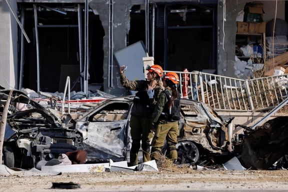 Israeli soldiers take selfies next to destroyed cars and a damaged residential building at an impact site following Iran's missile strike on Israel, in Be'er Sheva, Israel, June 20, 2025.