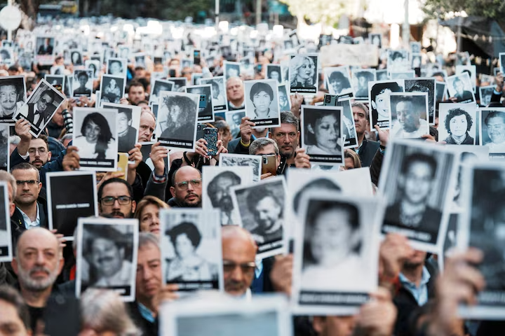 People hold images of the victims of the 1994 bombing attack on the Argentine Israeli Mutual Association (AMIA) community center, marking the 30th anniversary of the attack, in Buenos Aires, Argentina July 18, 2024. 