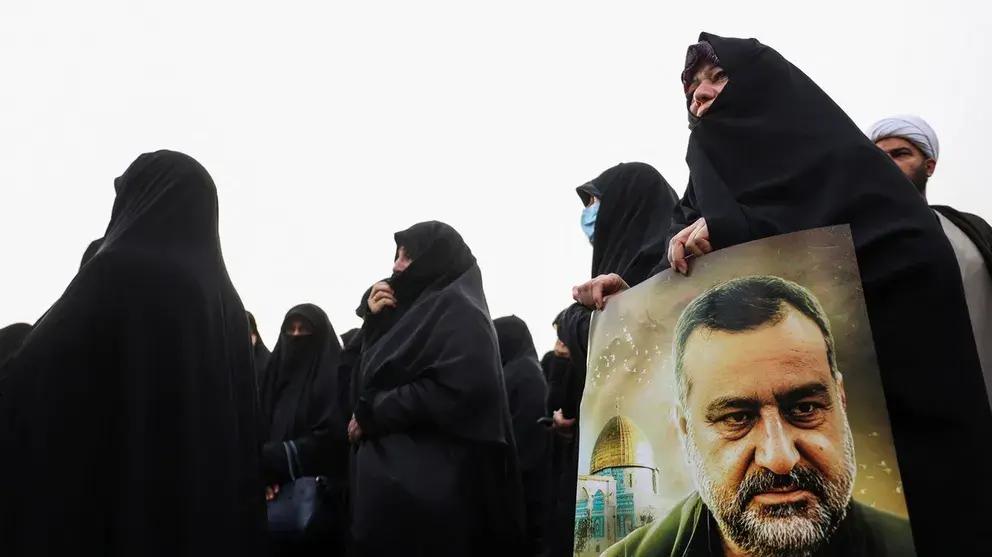 An Iranian woman carrying a poster of senior Iranian Revolutionary Guard general Razi Mousavi during his funeral service in Tehran (December 2023)