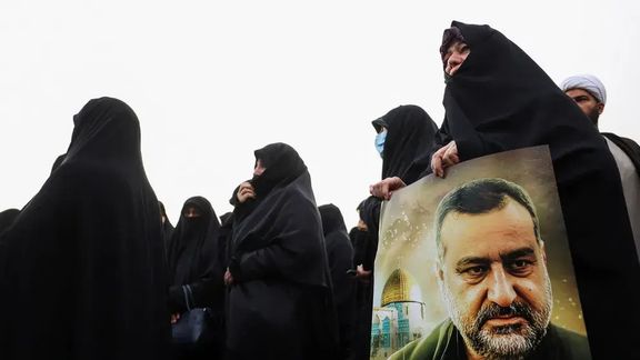 An Iranian woman carrying a poster of senior Iranian Revolutionary Guard general Razi Mousavi during his funeral service in Tehran (December 2023)