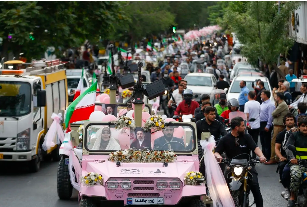 Couples ride in a decorated pink vehicle during a marriage-themed procession linked to pro-government rallies in Tehran.