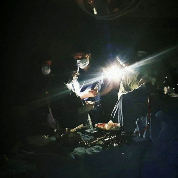 Surgeons continue an operation during a blackout in Iran, relying on flashlights for light.